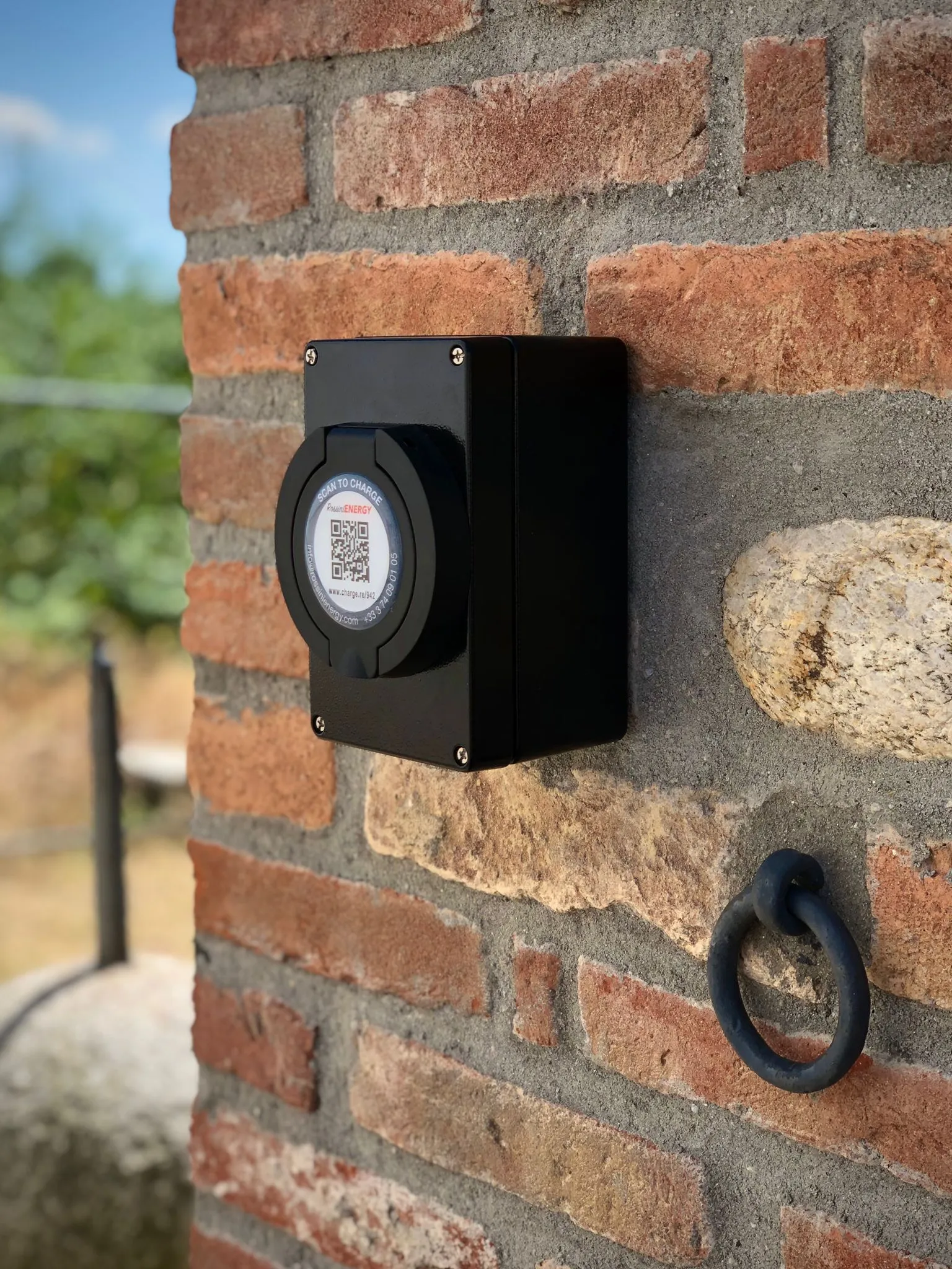 Borne de recharge murale fixée sur façade avec voiture électrique